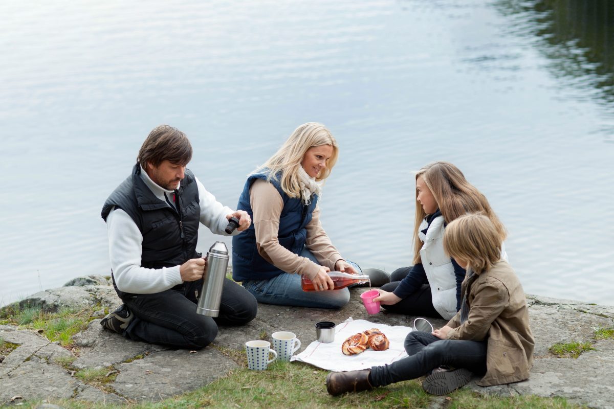 Familie på fire har piknik ved vannet