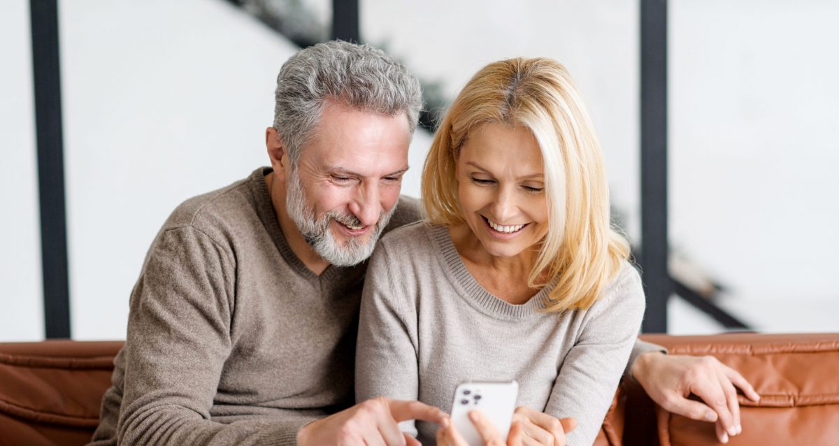 Mann og kvinne som sitter i en sofa og ser på en telefon