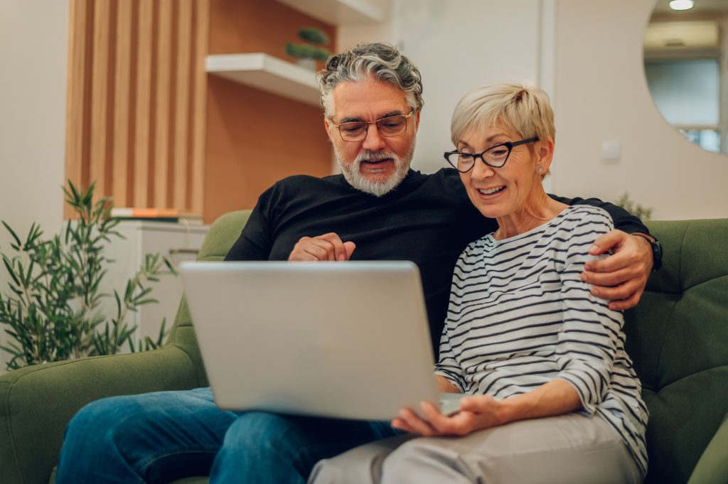 Eldre par ser på PC i sofaen